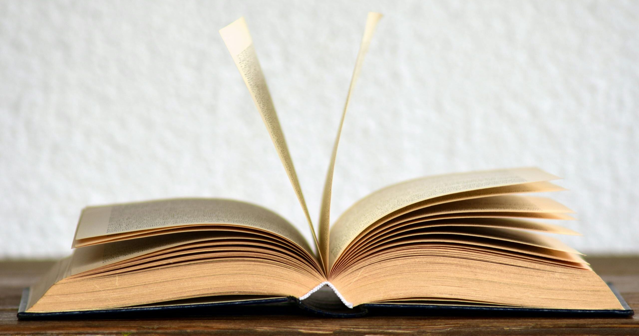 Close-up image of an open book with pages turning, creating a dynamic visual.